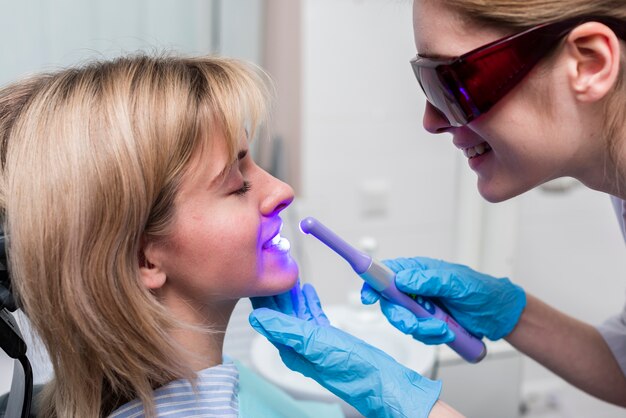 Dentist applying whitening gel as part of teeth whitening Denver procedure.