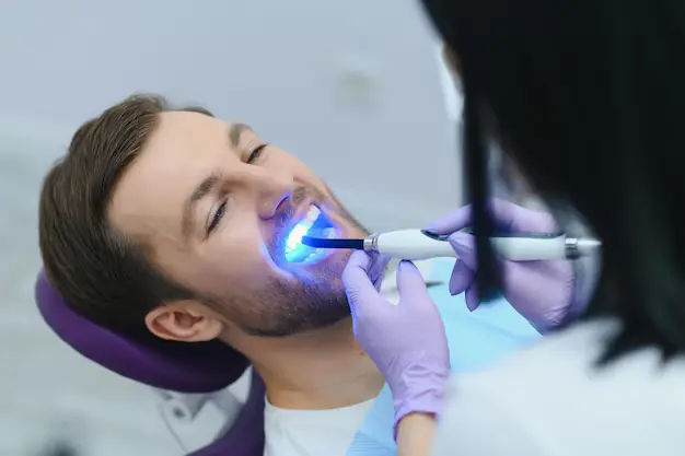 Patient receiving LED light treatment during professional teeth whitening Denver service