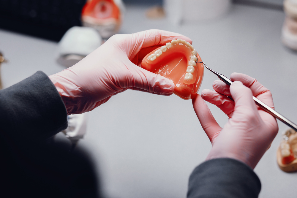 Close-up of a dental professional preparing a prosthetic tooth for restorative treatment in Denver.